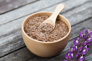 flax seeds in bowl and spoon on dark wooden background.