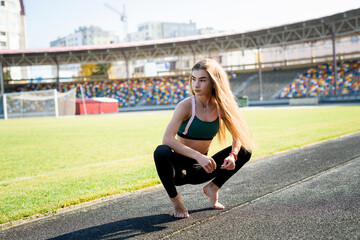 Fototapeta na wymiar Young sportive woman making morning exercises outdoors on the stadium