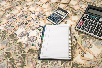 Empty notepad with calculator on Ukrainian Money backgrounds. 500 banknotes. Hryvnia (UAH). Top view