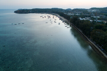 Fototapeta premium Aerial view drone shot of long tail boats at rawai beach in phuket Thailand sunset evening time.