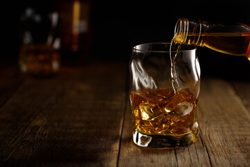 Pouring whiskey drink into a glass with ice.