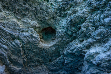 Background with a textured gray rock surface with a hole