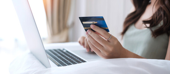 Happy woman holding credit card and using computer laptop for online shopping while making orders...