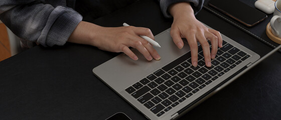 Fototapeta premium Hands typing on laptop keyboard on modern office desk with smartphone and coffee cup
