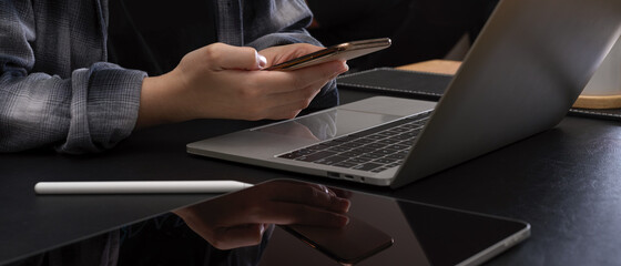 Female worker using smartphone while working at modern office desk