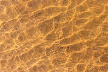 Texture of ripple sea water with sand bottom for background