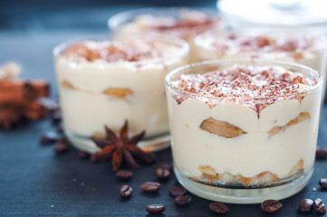 exquisite tiramisu in glasses decorated with cocoa powder on a dark background