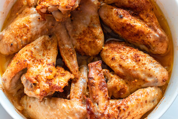 Grilled chicken wings with spices in a white bowl on the table, top view, flat lay