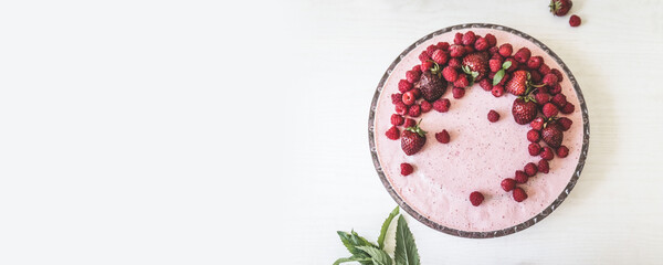 Berry cream pie with strawberries, raspberries in a glass dish on a white table, top view, flat lay
