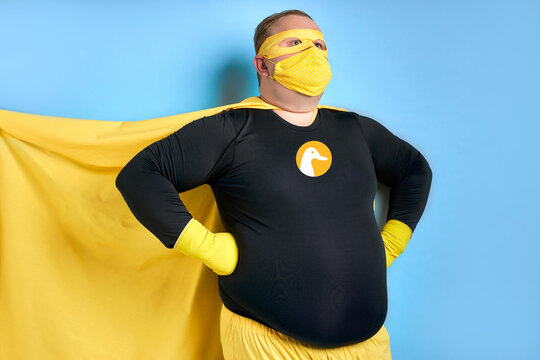 cleaning superhero saves the world from dirt, man has duck picture on costume, he is in yellow wear and in protective gloves, posing isolated over blue background