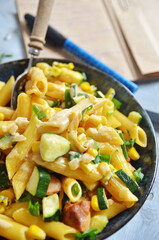 Tube noodles with chicken and corn in a bowl on a light background