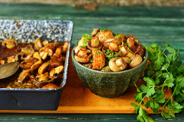 Baked balsamico mushrooms in a green bowl on a chopping board