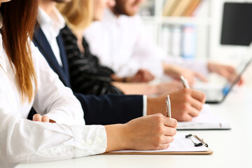 Group of people hold silver pen ready to make note in clipboard pad sheet closeup. Training course, university practice homework, school or college exercise, secretary table management concept