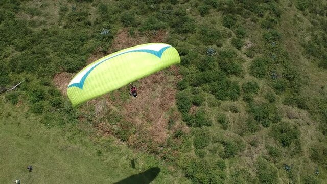 Paraglider ready to take off. Green colorful parachute. Aerial drone view of group of people for early morning flight. Competitions pilots of the paraglider.