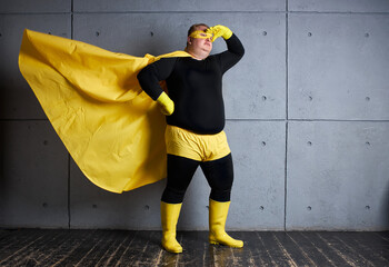 superhero fat man loking for danger and problems that he can solve, looks side. isolated gray background