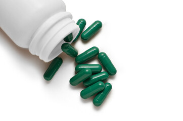 Green capsule pills and bottle isolated on white background