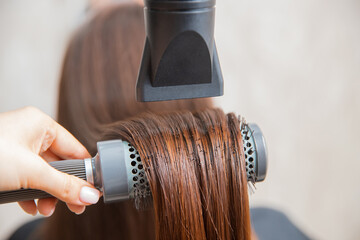 Close-up hair care in beauty salon, spa effect, master dries hairdryer
