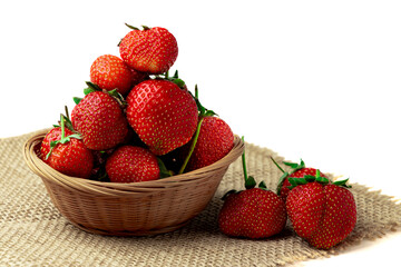 Strawberry. Close-up of sweet ripe fragrant strawberries in a basket on burlap isolated on a white background.