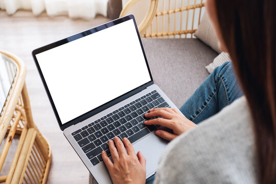 Top view mockup image of a woman working and typing on laptop computer with blank screen while sitting on a sofa at home