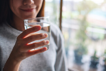 Closeup image of a beautiful young asian woman holding a glass of water to drink