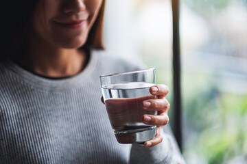 Closeup image of a beautiful young asian woman holding a glass of water to drink