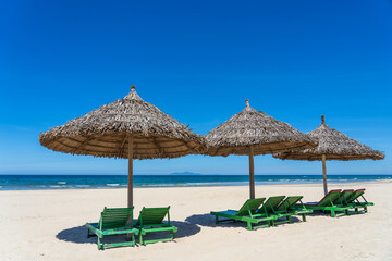 Tropical sand beach and summer sea water with blue sky and straw umbrella. Travel and nature concept