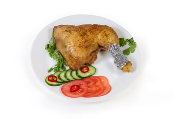Fried chicken leg served with vegetables on the dish