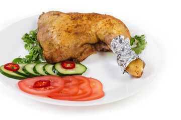 Fried chicken leg served with vegetables on dish close-up