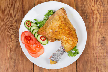 Fried chicken leg with vegetables on dish on rustic table