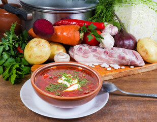 Red beetroot borscht in clay bowl against its raw ingredients