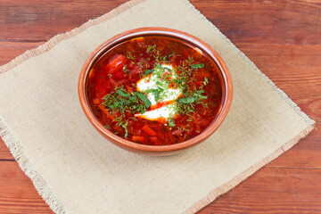 Red beetroot Ukrainian borscht in ceramic bowl on rustic table