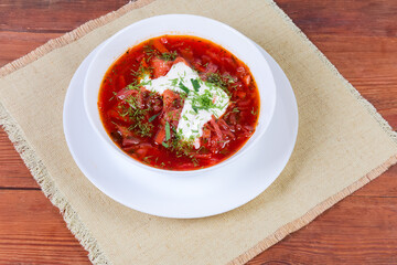 Red beetroot Ukrainian borscht in white bowl on rustic table
