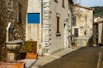 Fototapeta na wymiar The village of Mons in the country of Calian. Medieval village in the South of France. Fountain decorated with a bust. Sunny street. 