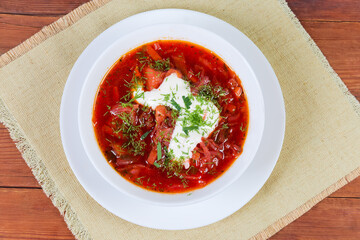 Red Ukrainian borscht in bowl on rustic table, top view