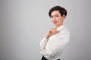 Confident young businesswoman posing in studio.Beautiful white female model in 30s wearing formal white t-shirt,classic red lipstick & bob haircut looking in camera with friendly smile,confident look