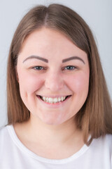 Fototapeta premium Pretty young plus size woman with friendly toothy smile.Beautiful Caucasian female model smiling in camera with white teeth and cheerful expression.Attractive cheeky girl with friendly smile