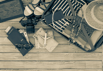Above view of travel female accessories, luggage and personal items, camera, maps, boarding pass, on wooden background - concept of travel and freedom