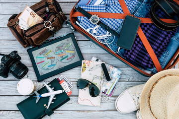 Above view of personal accessories of traveler ready for summer vacation, luggage, documents, camera - wood background