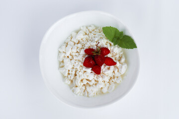 fresh diet curd homemade in a white plate with ripe strawberries and mint leaf on white background from boards. healthy breakfast option