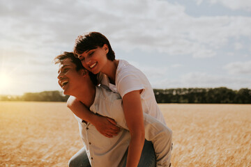 a woman on the back of a man having fun in a wheat field