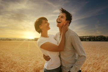 portrait of a laughing couple in a wheat field under a sunset