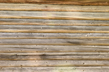 The old wall of the house is made of wooden logs with cracks