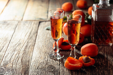 Homemade apricot liquor or grappa and fresh apricots on a old wooden table.