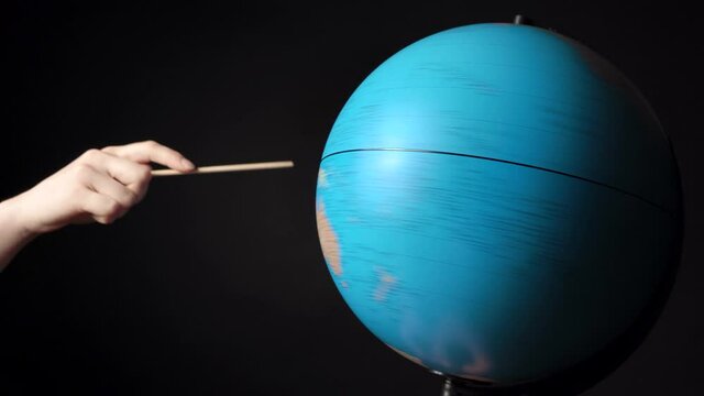 Shooting of rotating around blue globe with hand and pointer