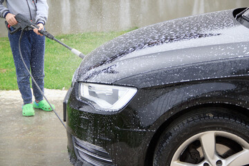 Cleaning car using high pressure water. Manual car wash under water pressure. 

