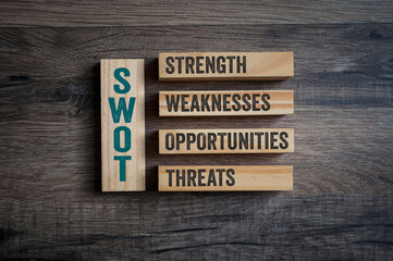 Wooden pieces with acronym SWOT, Strength, Weaknesses, Opportunities and Threats on wooden...