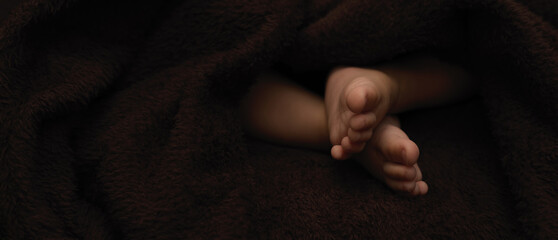 Tiny feet newborn baby, dark background