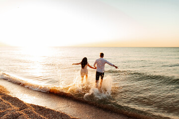 Loving couple in white clothes during a honeymoon at sea walk on the sand at a photoshoot Love Story, ocean coast, beach