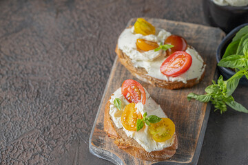 Appetizer bruschetta with bread, cream cheese and  tomato cherry on wooden cut board.Copy space