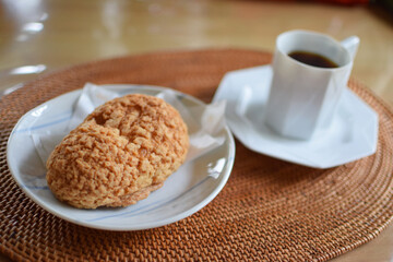 a cream puff and cup of coffee set / ハードタイプ・シュークリームとブラックコーヒー（斜めアングル）